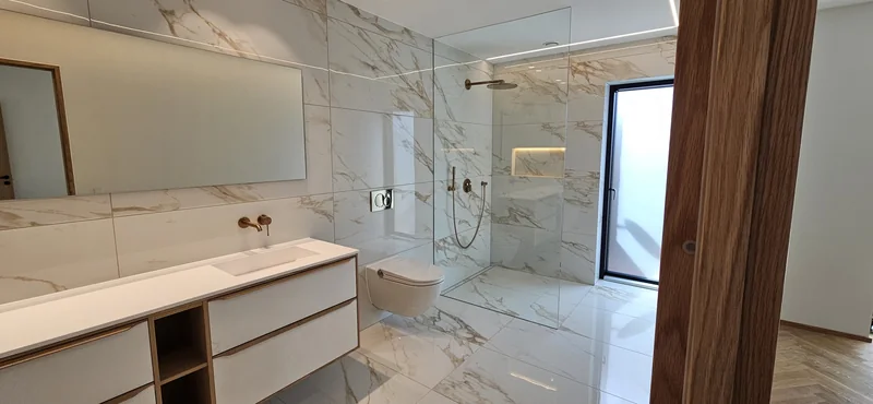 Håndvask, væghængt toilet og indbygget bruser.